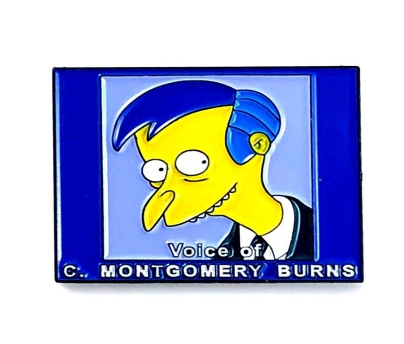 Puede incluir: Pin de esmalte azul y amarillo con un personaje de dibujos animados con el texto "Voice of C. Montgomery Burns".