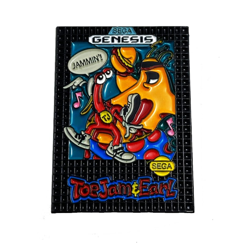 May include: A rectangular pin featuring the Sega Genesis game "ToeJam & Earl." The pin shows the game's characters, ToeJam and Earl, in a colourful, cartoonish style. The pin includes the text "JAMMIN'!" and the Sega logo.