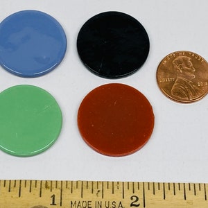 May include: Four round, flat, plastic chips in blue, black, green, and orange. The chips are about the size of a US penny.