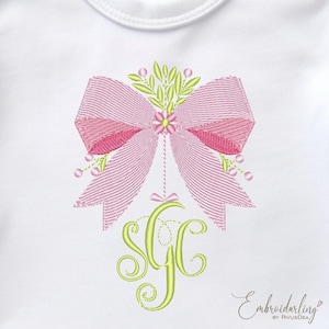 May include: A white onesie with a pink and green embroidered bow and the monogram "SGC" in green.