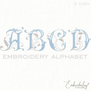Puede incluir: Un diseño de alfabeto bordado con las letras A, B, C y D en azul claro con detalles florales decorativos. Las palabras "EMBROIDERY ALPHABET" están debajo de las letras. La imagen también incluye el texto "3 SIZES".