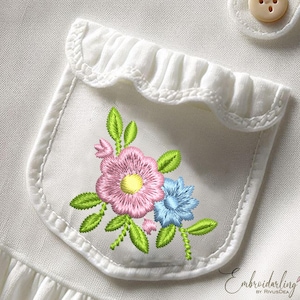 May include: A white fabric pocket with a scalloped edge, embroidered with a pink and blue floral design. The pocket is on a white garment.
