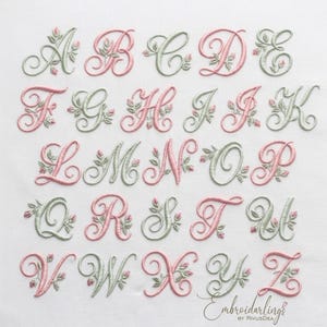 Peut inclure: Un ensemble d'alphabet brodé présentant des lettres majuscules cursives de A à Z. Chaque lettre est décorée de petites feuilles vertes et de boutons de rose roses. Les lettres alternent entre les couleurs de fil rose et vert. Le texte Embroidarlings by RivusDea est visible.