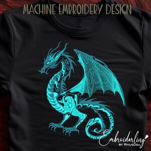 May include: Machine embroidery design of a teal blue dragon with wings spread wide. The dragon is on a black t-shirt.