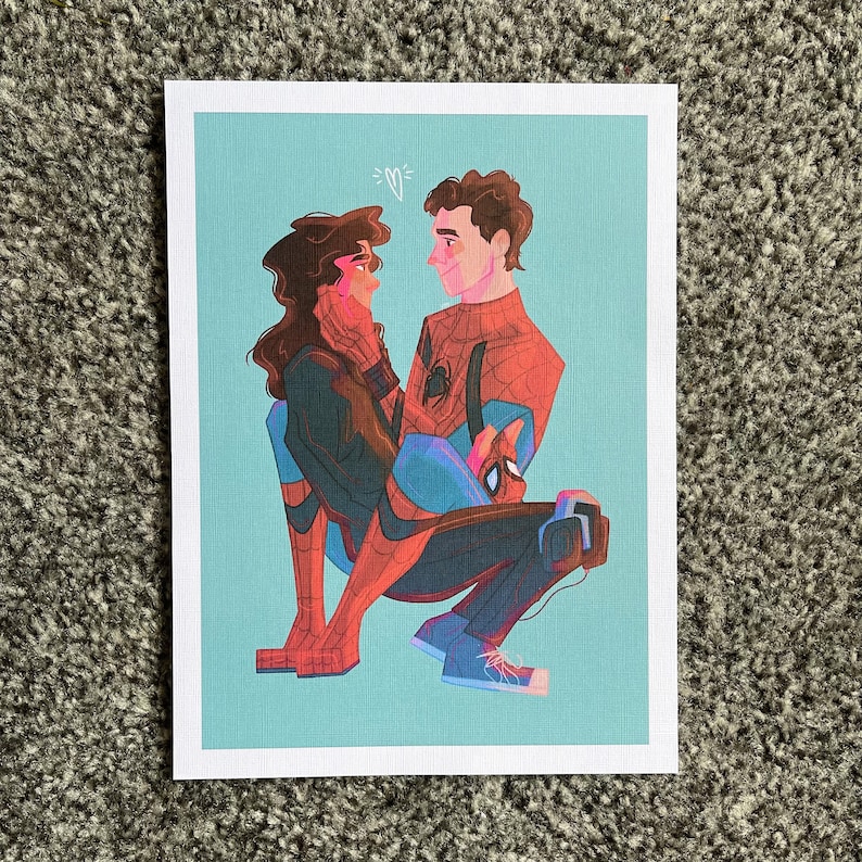 May include: A print featuring a couple in a tender embrace, with the man in a Spider-Man suit. The artwork has a light blue background and a small heart above the couple's heads. The man is wearing a red and blue Spider-Man suit.