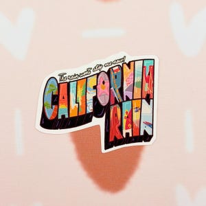 May include: A vibrant sticker displaying "CALIFORNIA RAIN" in a postcard design. The sticker uses a range of colours, including blue, orange, and red, with the text "The rain won't stop me now!" above the main text.