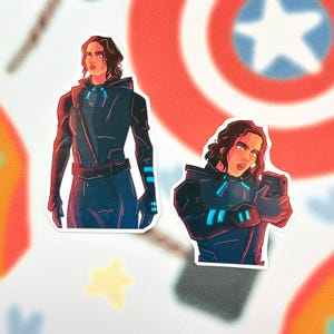 May include: Two stickers featuring a character in a dark blue outfit with glowing blue accents. The character has dark hair and a determined expression. The stickers are on a background with a Captain America shield design.