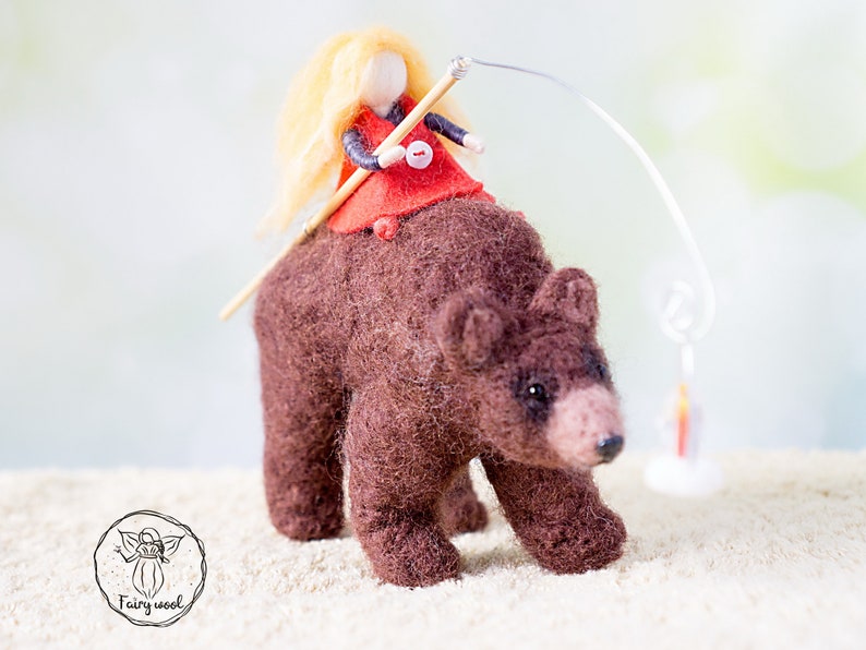 May include: A brown felt bear with a blonde felt doll riding on its back. The doll is holding a stick and a string with a small felt lantern at the end.