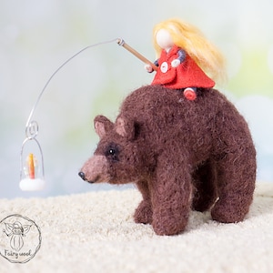 May include: A felt doll with blonde hair wearing a red coat rides a brown felt bear. The bear is walking towards a small lantern with a lit candle.