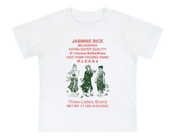 May include: White t-shirt with a green and red graphic of a rice bag featuring three ladies in traditional clothing. The text on the bag reads "Jasmine Rice Milagrosa Extra Super Quality" in English and Thai, "Gạo Thơm Thuộc Hàng" in Vietnamese, and "頂上茉莉香米" in Chinese. The text at the bottom reads "Three Ladies Brand Net Wt. 21 lbs (9.52 kgs)".