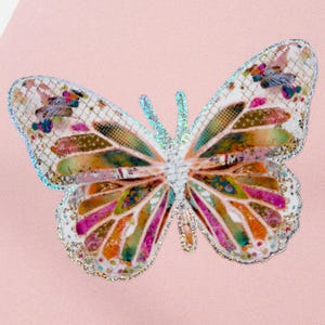 May include: A colorful butterfly with iridescent wings, featuring a patchwork design of various colors and textures. The butterfly is on a pink background.