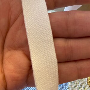 May include: Close-up of white cotton webbing, showing the woven texture. The webbing is thick and appears to be strong.