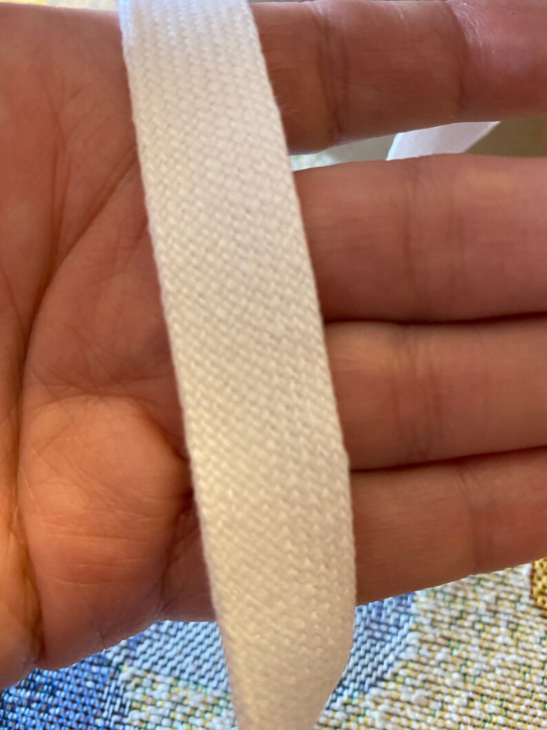 May include: Close-up of white cotton webbing, showing the woven texture. The webbing is thick and appears to be strong.