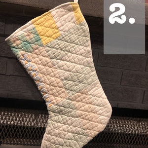 May include: A patchwork quilted Christmas stocking with a white background and yellow, green, and pink squares. The stocking is hanging on a fireplace mantel.