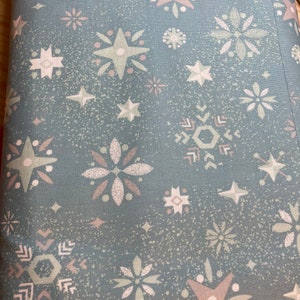 May include: A teal fabric with a repeating pattern of white, pink, and green stars, snowflakes, and geometric shapes.