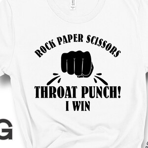 May include: White t-shirt with black text that reads "Rock Paper Scissors Throat Punch! I Win". A black fist is shown punching through the text.