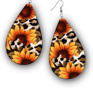 May include: A pair of teardrop-shaped earrings featuring a sunflower design with a leopard print background. The earrings have a brown border and silver-colored hooks. The sunflowers are yellow and orange.