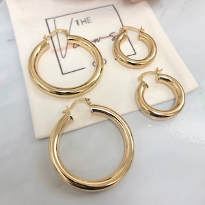 May include: Three gold hoop earrings of different sizes. The largest hoop is about 2 inches in diameter, the middle hoop is about 1.5 inches in diameter, and the smallest hoop is about 1 inch in diameter.