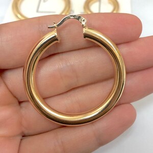 May include: A pair of gold hoop earrings. The earrings are thick and have a smooth finish.