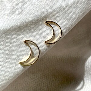 May include: A pair of gold crescent moon earrings. The earrings are simple and delicate, and would make a great gift for a friend or loved one.