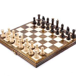 Peut inclure: Un échiquier en bois avec des cases noires et blanches. Le plateau est ouvert et montre une partie d'échecs en cours. Les pièces blanches sont en bois clair et les pièces noires en bois foncé.