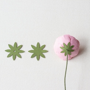 May include: Two green paper flower embellishments with a hole in the center and a pink paper flower with a green paper stem.