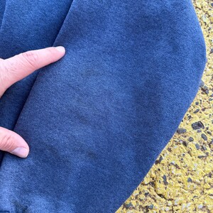 May include: Close-up of the blue fabric of a sweatshirt sleeve. The fabric has a slightly textured appearance.