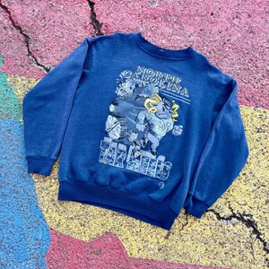 May include: A blue sweatshirt with a graphic of the University of North Carolina Tar Heels mascot, a ram, with the text "North Carolina Tar Heels" and "UNC" printed on the front.