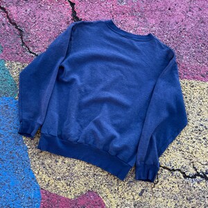 May include: A dark blue long-sleeved sweatshirt with a crew neck.