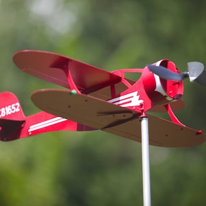 May include: Red metal airplane wind spinner with a white propeller and the text "NC81652" on the tail.
