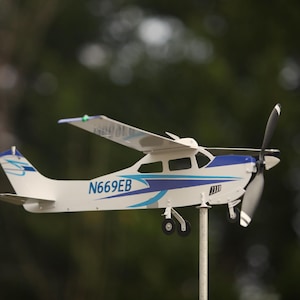 May include: A white and blue model airplane with a propeller, the tail reads "N669EB".
