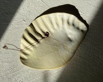 Bandeja artesanal em cerâmica com formato de folha, azul claro, peça decorativa escultural em estilo minimalista.