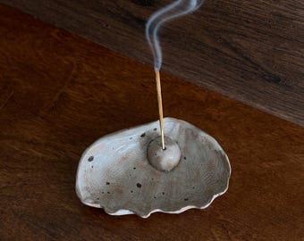 Porta-incenso artesanal em cerâmica com formato de concha, ideal para decoração de casa de praia.