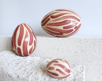 Conjunto de ovos de cerâmica artesanais pintados à mão em tons de vermelho e bordô para decoração de mesa.