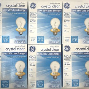 May include: Six boxes of GE Crystal Clear energy-efficient halogen light bulbs. Each box features a light bulb graphic, the text "Uses 28% Less Energy," and specifications including 60W replacement, 43W usage, 750 lumens, and a 0.9-year life.