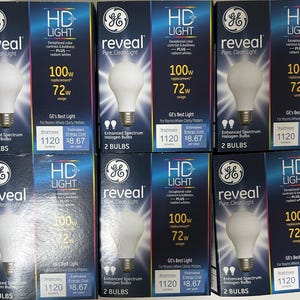 May include: Multiple boxes of GE Reveal HD Light bulbs. Each box features a white light bulb, the text "reveal Pure, Clean Light", and details about brightness and energy cost. The boxes are blue and white.