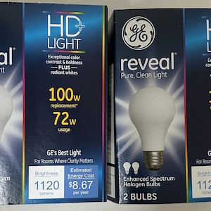 Może przedstawiać: Dwa pudełka żarówek GE Reveal HD LIGHT. Każde pudełko przedstawia białą żarówkę. Tekst na pudełkach zawiera "reveal", "Pure, Clean Light", "HD LIGHT", "100w zamiennik" i "72w zużycie".