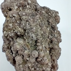 May include: A close-up of a rough, gray and brown rock with a textured surface. The rock is covered in small, round nodules.