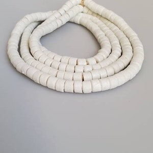 May include: A white ceramic bead necklace with a simple design. The necklace is made of multiple strands of beads, creating a layered effect.