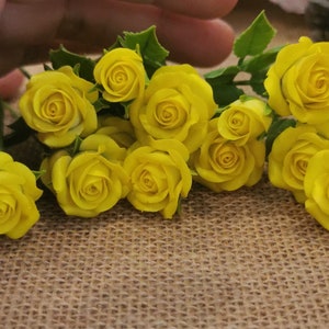 May include: A bouquet of yellow roses with green leaves, arranged on a brown hessian background.
