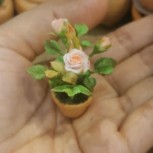 Op de afbeelding: Een set van drie keramische mokken met een gespikkelde, crèmekleurige glazuur. Elke mok heeft een ander handgeschilderd bloemmotief in tinten blauw, groen en geel. De mokken hebben een eenvoudige, afgeronde vorm en een comfortabele handgreep.