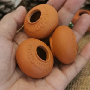 Puede incluir: Tres pequeñas macetas de terracota con un diseño decorativo alrededor del borde. Las macetas son sin esmaltar y tienen un color marrón natural.