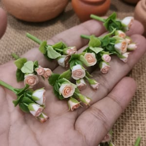 May include: A collection of miniature peach-colored roses with green leaves. The roses are arranged in a bouquet and are perfect for dollhouses or other miniature projects.