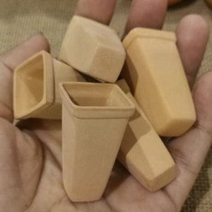 May include: A collection of six small, terracotta-colored, rectangular planters. The planters are arranged in a hand, with the tallest planter in the center.