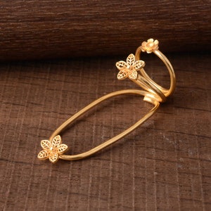 May include: Gold-toned ring with three delicate flower designs. The ring is open and can be worn on multiple fingers.
