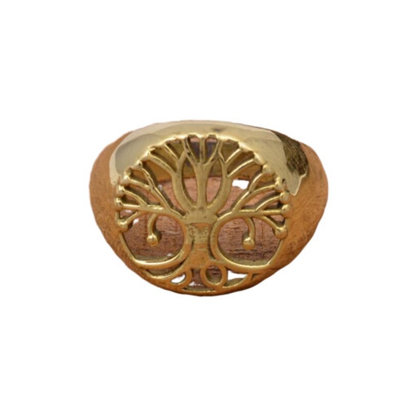May include: A gold-colored ring featuring a tree of life design. The ring has a rounded band and a detailed cutout of a tree with branches and roots. The ring is likely made of brass or a similar metal.