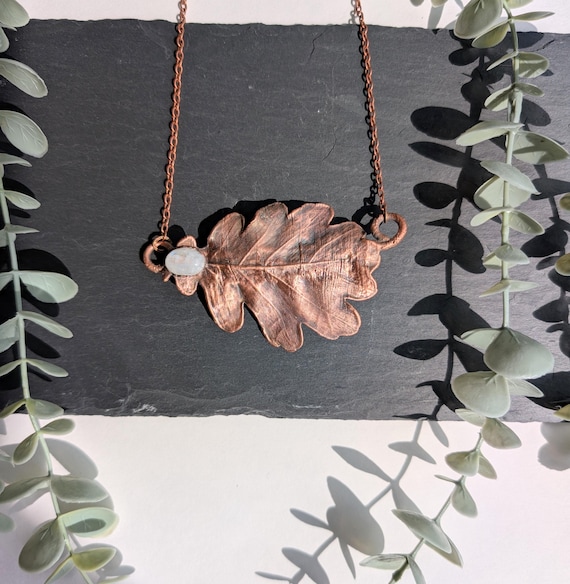A real oak leaf electroformed in copper with a moonstone center — actual nature preserved in metal, wearable botany with 18 fans already nodding along.