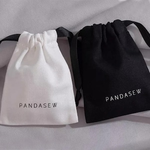 May include: Two drawstring pouches, one white and one black, both featuring the text PANDASEW printed in a simple sans-serif font. Each bag has a matching black ribbon drawstring closure at the top, creating a gathered effect when pulled shut.