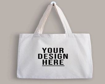 Könnte beinhalten: Eine weiße Tragetasche mit cremefarbenen Henkeln und dem Text "YOUR DESIGN HERE" in fetten schwarzen Buchstaben. Die Tasche hängt vor einem neutralen Hintergrund und zeigt ihr schlichtes Design und ihr Personalisierungspotenzial.
