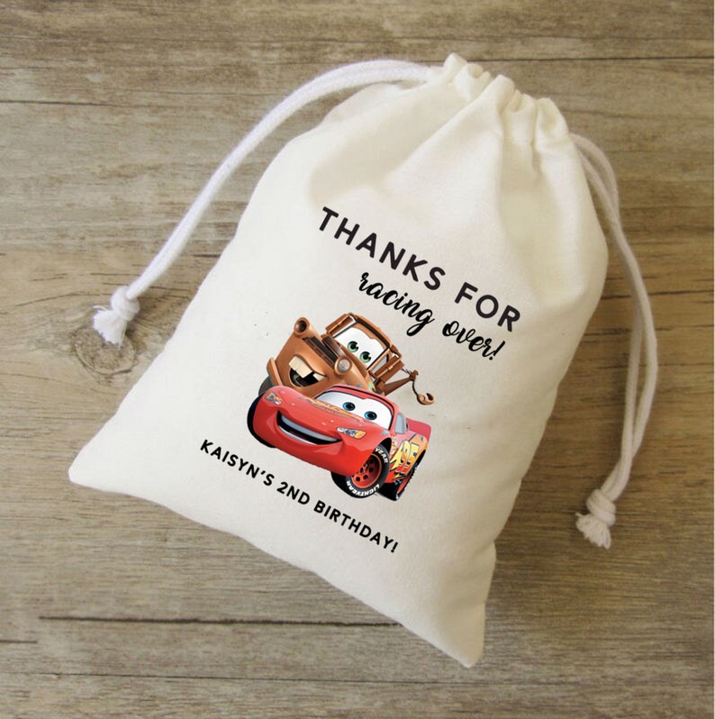 Puede incluir: Una bolsa de algod&oacute;n blanco con cord&oacute;n de ajuste con un dise&ntilde;o de Cars. La bolsa presenta a Rayo McQueen y Mate con el texto "&iexcl;Gracias por correr! &iexcl;Kaisyn's 2nd Birthday!"